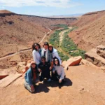 Group of travelers on a Morocco Atlas Mountains tour overlooking a green valley oasis