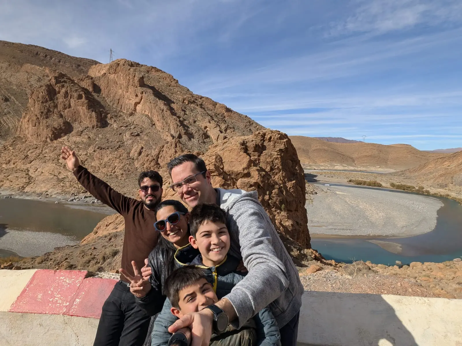 Happy family on a Morocco travel packages trip posing by a river in the Atlas Mountains, Morocco