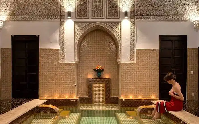 Woman relaxing after a hammam in Morocco inside a traditional riad spa with candles and Moroccan tile