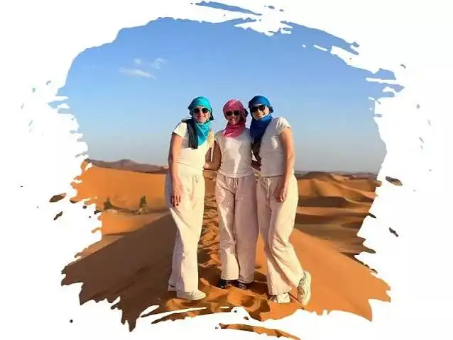 Morocco tours from Australia - three women enjoying a Sahara Desert camel trek at sunset