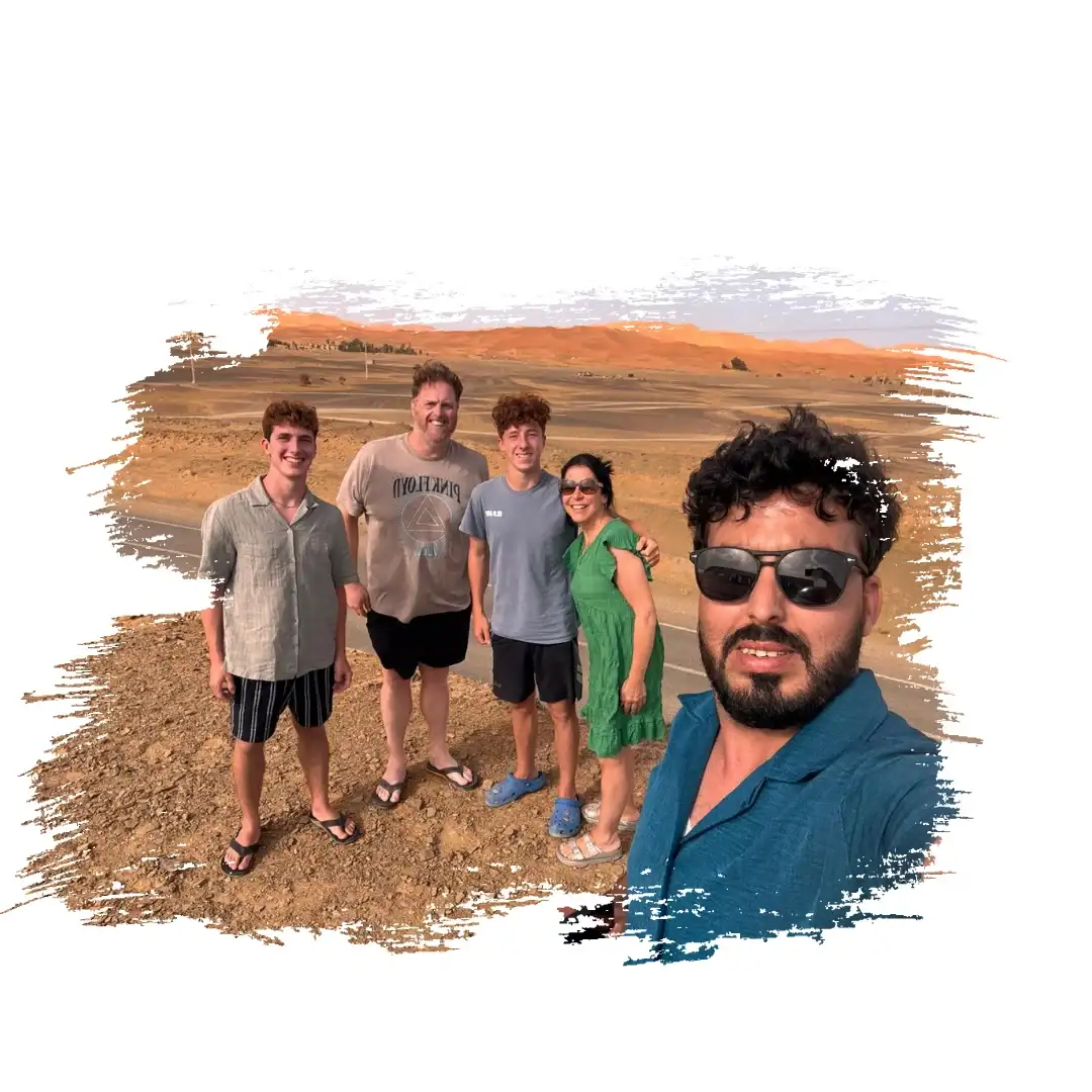 Advisor Morocco Tours – Happy Travelers with Their Local Guide in the Desert Group of travelers and their local guide taking a selfie in the Moroccan desert during a Morocco tour